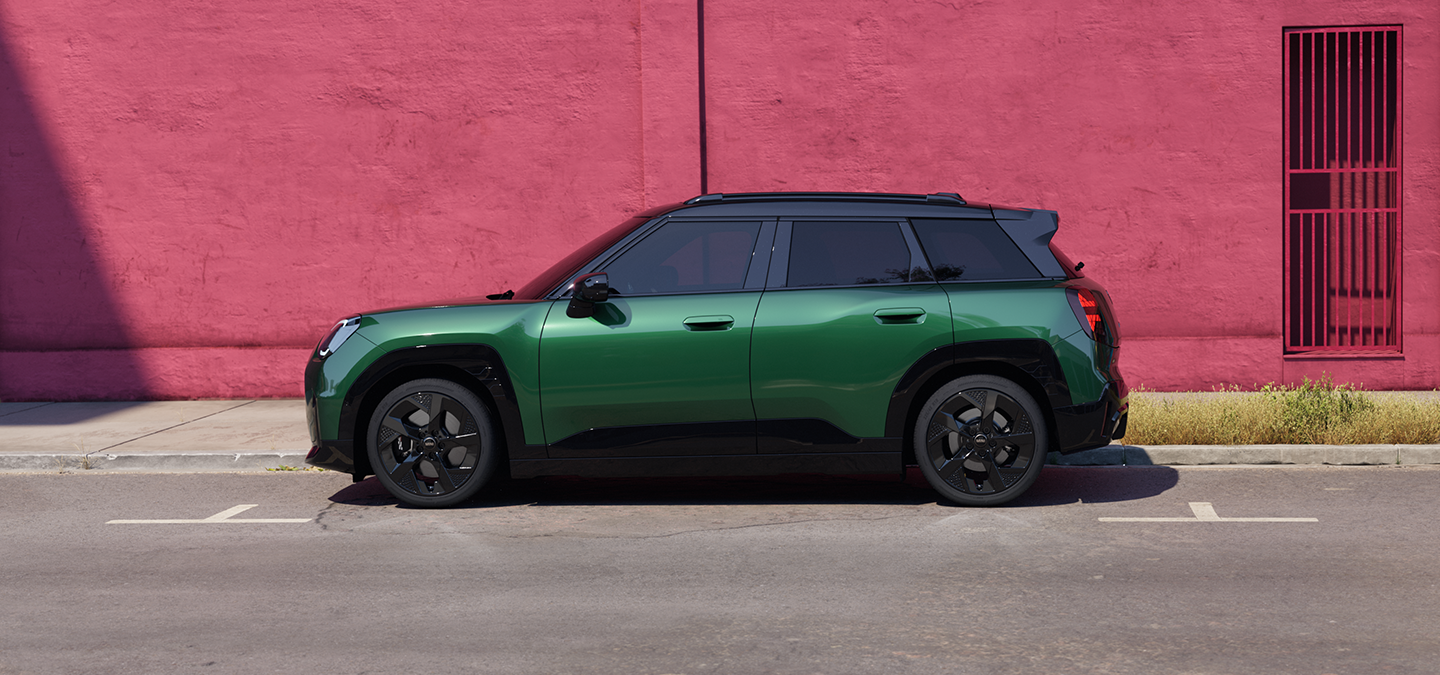 Vue latérale de la MINI Aceman Electric British Racing Green avec toit noir en ville.