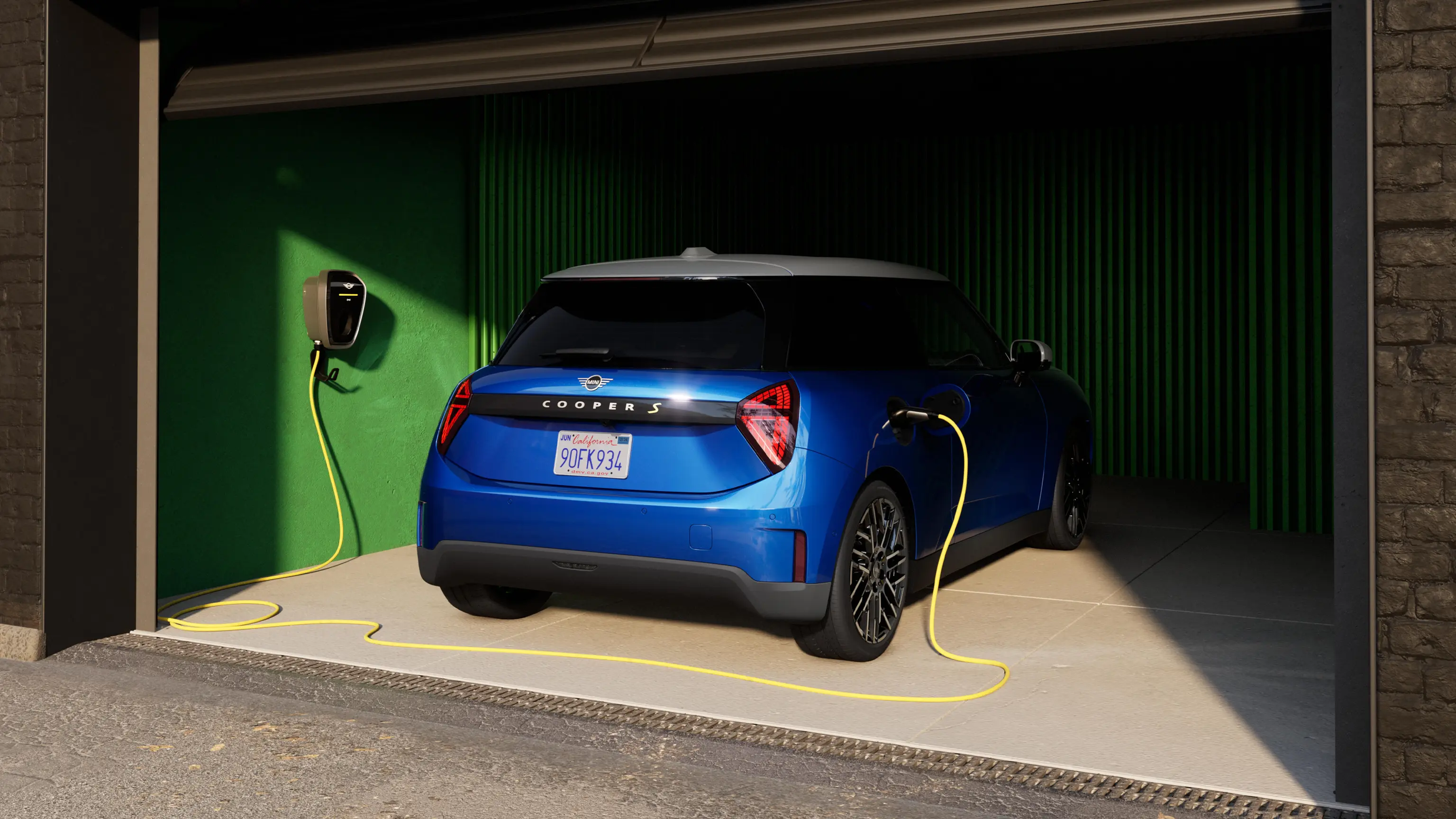 Vue arrière de la MINI Cooper 100% électrique Blazing Blue dans le garage avec le câble de recharge