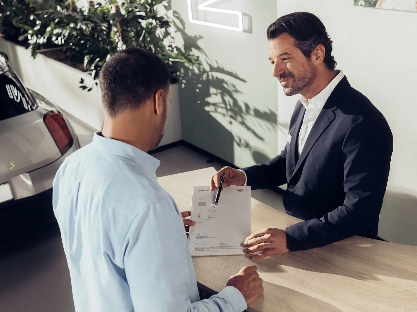 Ein Service Assistent bei einem MINI Partner berät einen Kunden über die Optionen der MINI Reifenversicherung.