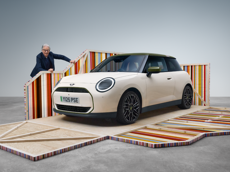 Frontansicht des vollelektrischen MINI Cooper Paul Smith Edition in Inspired White mit dem Designer Paul Smith